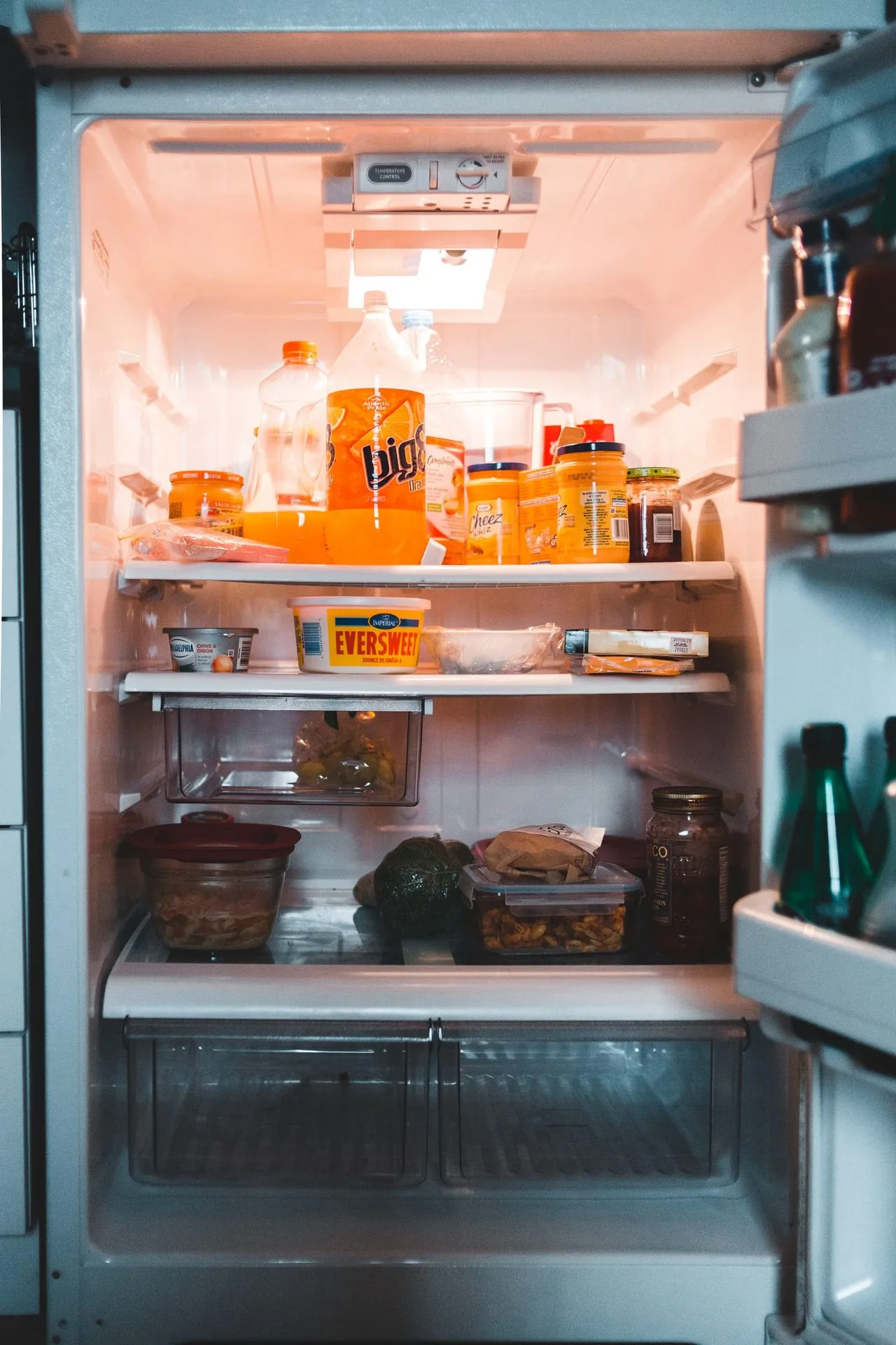 Photo of an open small fridge organized with bins and drinks