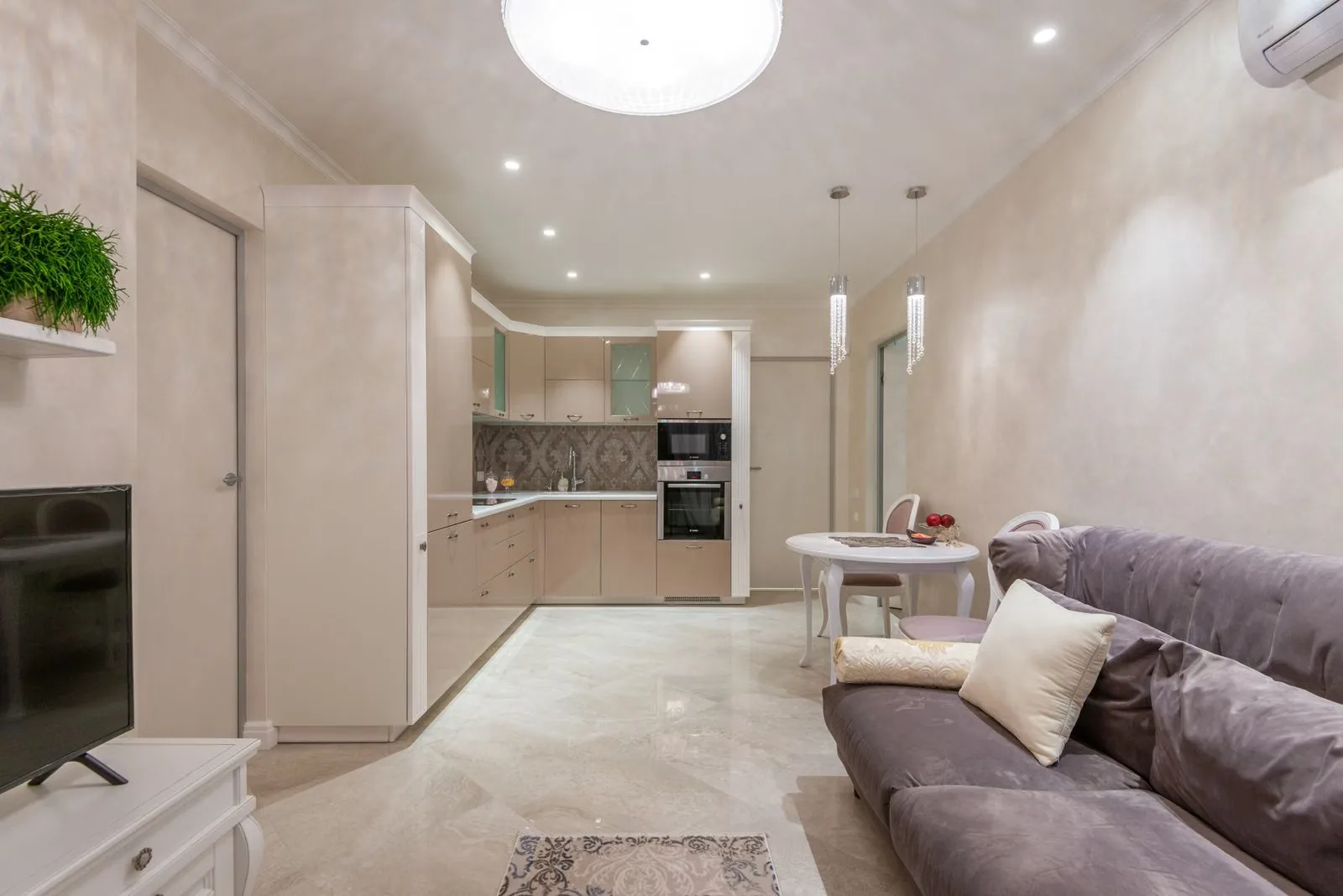 Photo of a bright organized studio apartment kitchen open to the living area